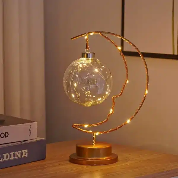 Lampe de table LED suspendue, design élégant avec une lumière douce et chaleureuse, posée sur une table près de livres.