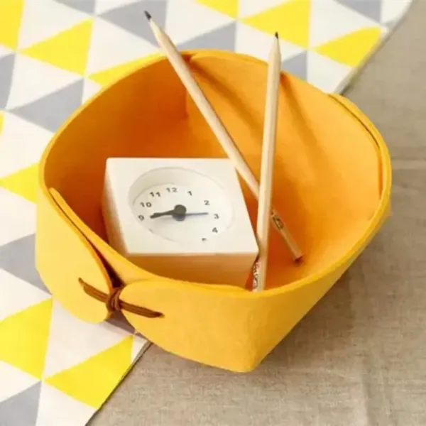 Panier de rangement en feutre jaune contenant des accessoires de bureau, idéal pour l’organisation et la décoration