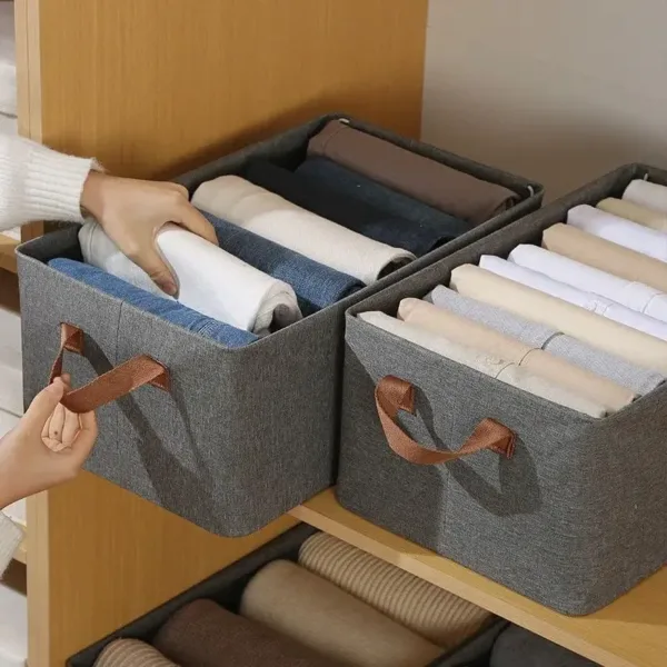 Boîte de rangement pliable en tissu avec poignées, parfaite pour organiser vêtements et accessoires dans un placard.