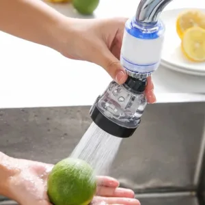 Filtre de robinet avec douchette rotative à 360 degrés utilisé pour laver un citron sous un jet d'eau dans une cuisine.