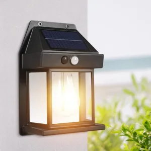 Lampe solaire murale noire avec détecteur de mouvement, installée sur un mur extérieur et émettant une lumière chaude.