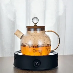 Théière en verre borosilicate avec couvercle doré pour infusions élégantes.