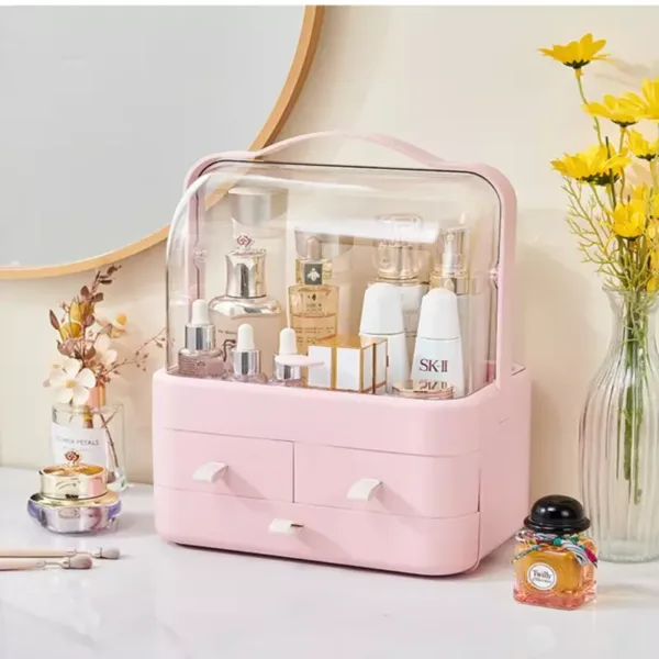 Organisateur maquillage rose avec couvercle transparent et tiroirs pour cosmétiques et accessoires.