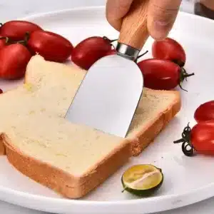Set d’ustensiles à fromage avec manches en bois et lames en acier inoxydable sur une planche.