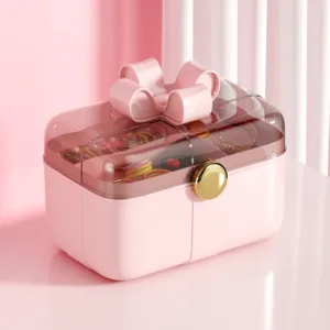 Boîte de rangement pour bijoux avec couvercle transparent et nœud décoratif.