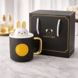 Mug lapin avec couvercle en céramique noire et anse dorée présenté avec coffret cadeau