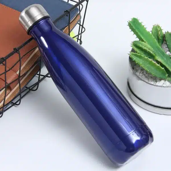 bouteille isotherme inox 500ml couleur bleu nuit posée à côté d’un carnet et d’un cactus