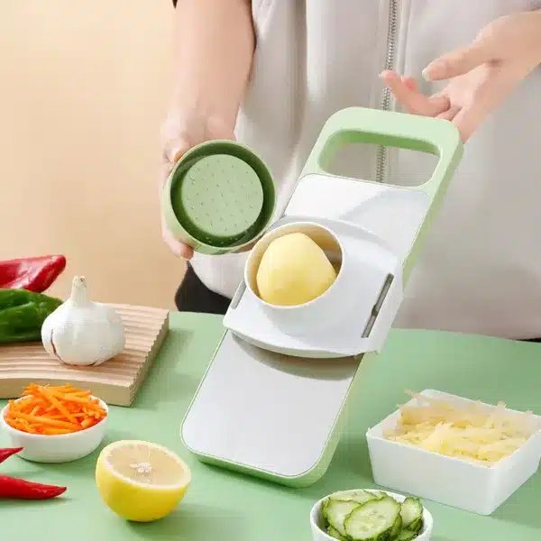 mandoline de cuisine multifonction avec bac, râpe à légumes verte en action sur plan de travail