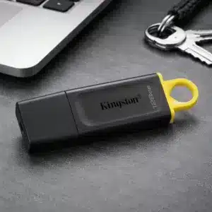 Clé USB Kingston 128Go noire avec anneau jaune posée près d’un ordinateur portable et de clés au Maroc