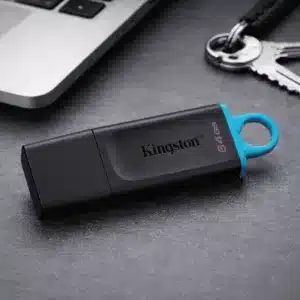 Clé USB Kingston 64Go noire avec anneau jaune posée près d’un ordinateur portable et de clés au Maroc