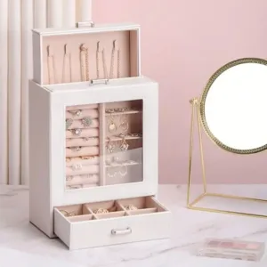 Boîte à bijoux verticale blanche avec vitrine transparente et tiroir ouvert sur une coiffeuse