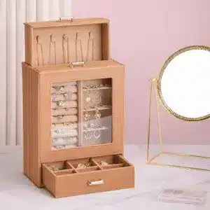 Boîte à bijoux verticale blanche avec vitrine transparente et tiroir ouvert sur une coiffeuse