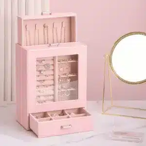 Boîte à bijoux verticale blanche avec vitrine transparente et tiroir ouvert sur une coiffeuse