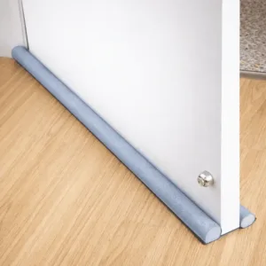 Bas de porte étanche anti froid glissé sous une porte blanche sur sol en bois
