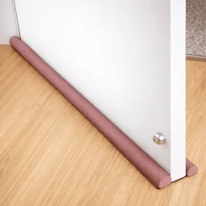Bas de porte étanche anti froid glissé sous une porte blanche sur sol en bois