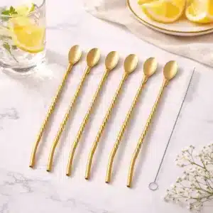 Set de pailles cuillères en inox doré réutilisables avec goupillon de nettoyage posé sur une table en marbre