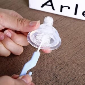 Brosse nettoyage biberon et tétine utilisée pour nettoyer un couvercle de biberon violet