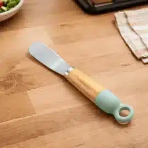 Couteau à fromage en inox manche bois vert coupant un morceau de fromage au Maroc