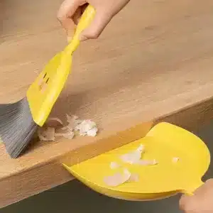 Mini balayette pelle Maroc en forme de canard jaune posée sur une table