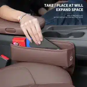 Organisateur de siège voiture en cuir noir installé entre le siège et la console centrale pour ranger téléphone, clés et accessoires.