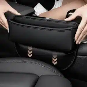 Organisateur de siège voiture en cuir noir installé entre le siège et la console centrale pour ranger téléphone, clés et accessoires.
