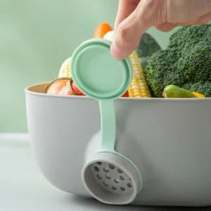 Bassine de cuisine grise avec bouchon de vidange et poignées intégrées pour laver et égoutter les fruits et légumes.